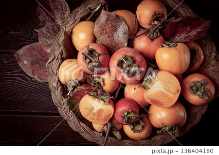 fresh persimmon in a basket, with leaves, top view, no people, fresh persimmon in a basket, with leaves, top view, no people, 136404180