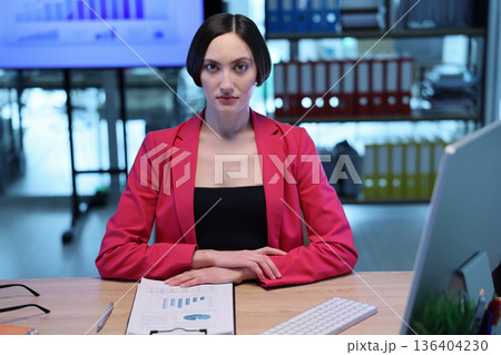 Confident businesswoman presents financial data in modern office space during afternoon meeting 136404230