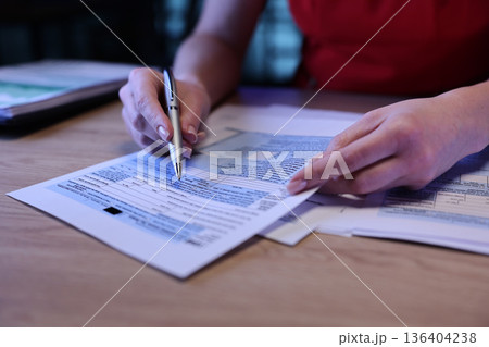 Focused attention on filling out important documents at a cozy cafe desk during the evening 136404238