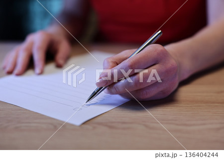 Completing a checklist while planning tasks at a cozy wooden table in a bright room Completing a checklist while planning tasks at a cozy wooden table in a bright room 136404244