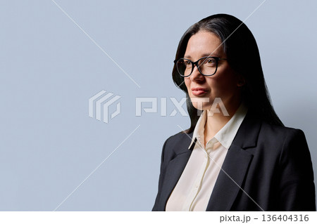 Profile view of serious confident business woman, gray background, copy space 136404316