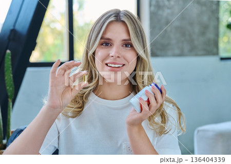 Close up of yellow Omega 3, fish oil capsule and bottle in hands of young woman 136404339
