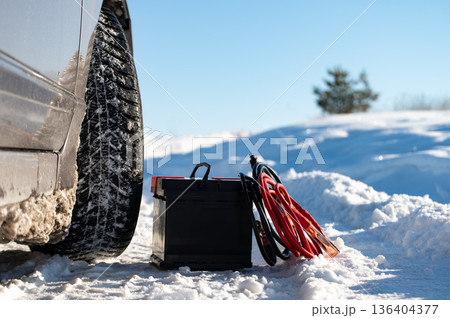 Car battery against the background of a car in winter. Winter battery discharge concept, copy space Car battery against the background of a car in winter. Winter battery discharge concept, copy space 136404377