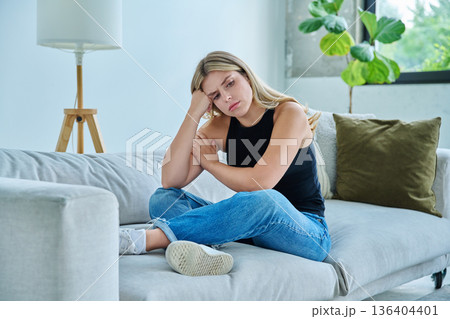 Unhappy upset young woman having headache, sitting at home 136404401