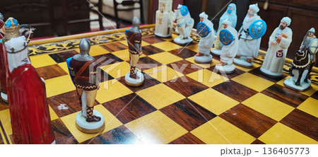 A close-up of a decorative chessboard with detailed medieval-style pieces. Conceptual representation of leadership, competition, decision-making, business strategy, and critical thinking. 136405773