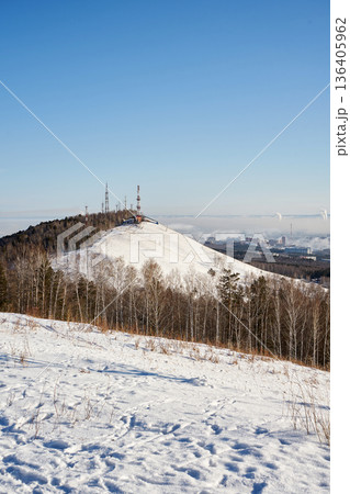 Winter landscape of Nikolaevskaya Sopka, Gremyachaya Griva park in Krasnoyarsk, Russia. Snow-covered hill with communication towers and a city view on a clear day Winter landscape of Nikolaevskaya Sopka, Gremyachaya Griva park in Krasnoyarsk, Russia. Snow-covered hill with communication towers and a city view on a clear day 136405962