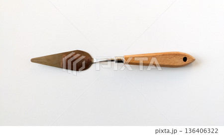 Wide metal palette knife with a wooden handle, top view. Art supplies for cleaning oil and acrylic paint from a palette. 136406322