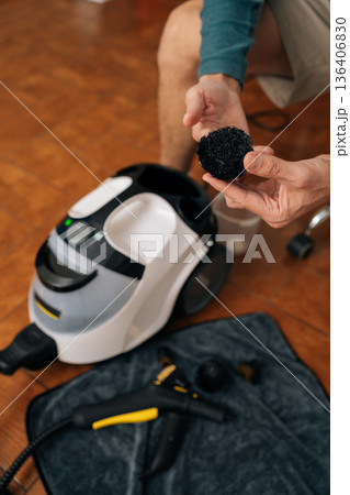 Vertical cropped shot person holding worn steam cleaner brush, demonstrating need for maintenance and replacement of cleaning equipment during domestic chores for home hygiene, close-up. Vertical cropped shot person holding worn steam cleaner brush, demonstrating need for maintenance and replacement of cleaning equipment during domestic chores for home hygiene, close-up. 136406830