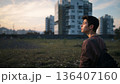 Person Standing in a Field Looking at Buildings During Sunset in an Urban Area 136407160