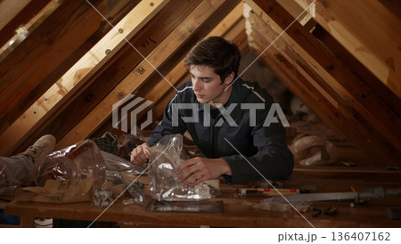 Young Person Works in an Attic on a Project With Tools and Materials During a Weekend 136407162