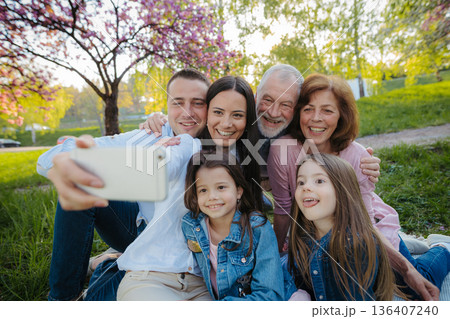 Three generation family sitting outside in spring nature, taking selfie. Three generation family sitting outside in spring nature, taking selfie. 136407240