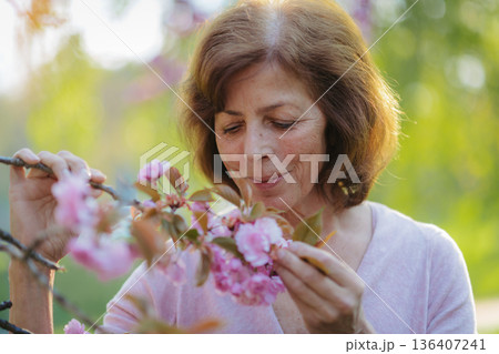 Beautiful senior woman standing outside in spring nature. Copy space. 136407241