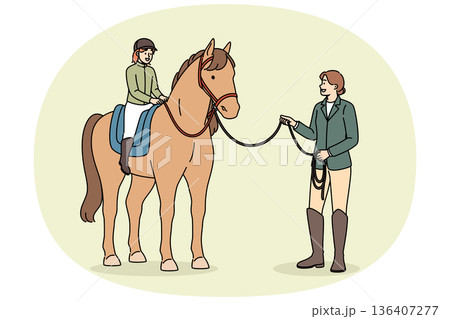 Little girl learns to ride horse and be jockey or rider, under supervision of female trainer 136407277