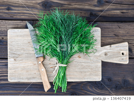 Fresh dill bunch tied with string on wooden cutting board Fresh dill bunch tied with string on wooden cutting board 136407419