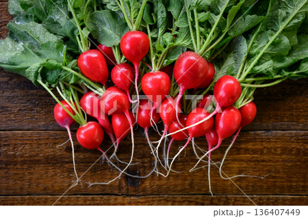 Whole red radishes with stems and roots on wooden surface 136407449
