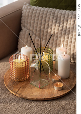 Candles and Reed Diffuser on Wooden Tray. Cozy Home Decor lifestyle with Cushions Candles and Reed Diffuser on Wooden Tray. Cozy Home Decor lifestyle with Cushions 136407459