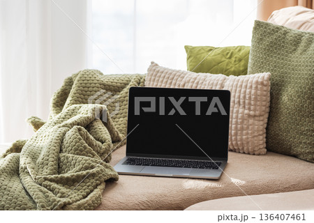 Laptop on Cozy Sofa with Textured Pillows and Blanket. Relaxed Home Workspace 136407461