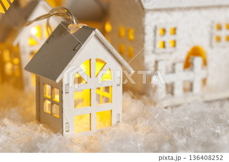 Christmas wooden houses garlands with lights in the snow on glowing lights bokeh background Christmas wooden houses garlands with lights in the snow on glowing lights bokeh background 136408252