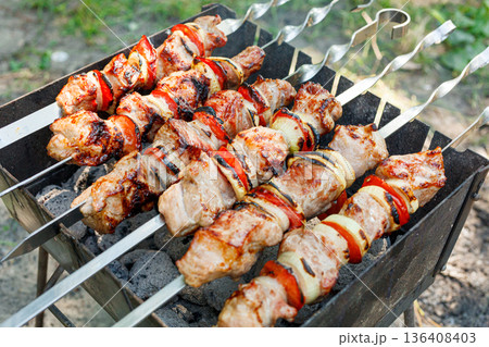 Cooking barbecue with vegetables on skewers. Roasted meat on the grill Cooking barbecue with vegetables on skewers. Roasted meat on the grill 136408403