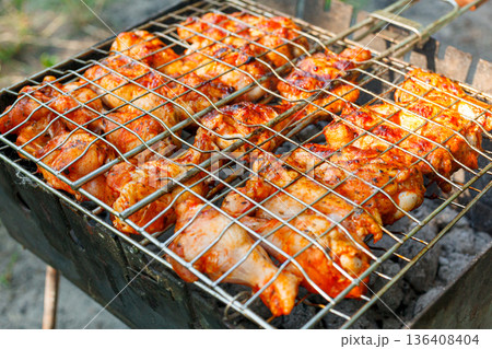 Cooking chicken wings and legs on the grill. Roasted meat on the grill Cooking chicken wings and legs on the grill. Roasted meat on the grill 136408404