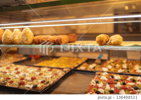 Traditional Italian street food including pizza slices and fried snacks displayed in a bakery showcase in the historic center of Rome. Italy 136408521