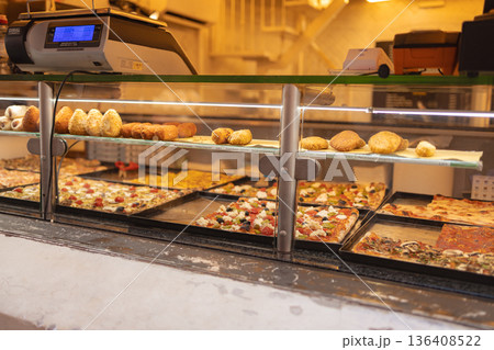 Traditional Italian street food including pizza slices and fried snacks displayed in a bakery showcase in the historic center of Rome. Italy 136408522