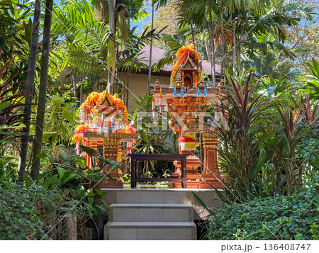 Tropical spirit shrine in lush garden with offerings 136408747