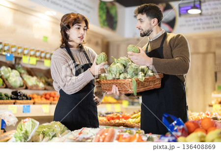 Man and woman seller putting artichokes Man and woman seller putting artichokes 136408869