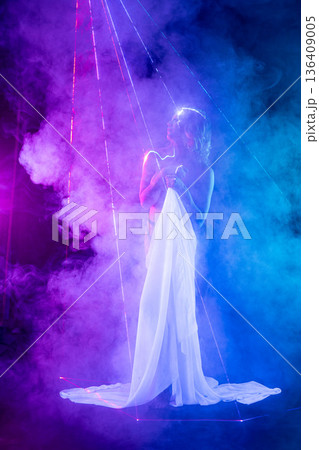Sensual woman in white drapery surrounded by purple smoke and laser beams in a futuristic setting. 136409005