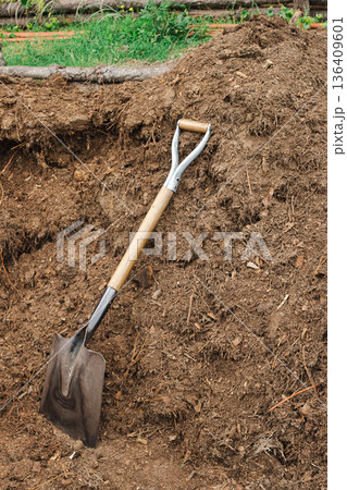 Shovel leaning on a large pile of nutrient-rich organic soil for sustainable gardening and reforesting 136409601
