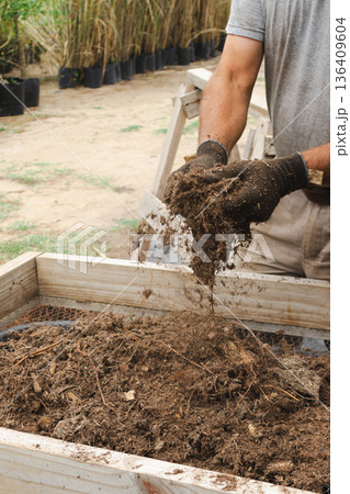 Worker screening compost for growing plants, protecting the land, and preparing for reforestation efforts Worker screening compost for growing plants, protecting the land, and preparing for reforestation efforts 136409604