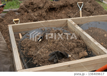 Sifting organic soil and compost for sustainable reforesting and garden preparation, using hand tools outdoors 136409617