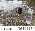 川辺でポータブル浄水器を使って水を確保するアウトドアの風景 136409954