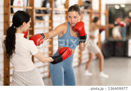 Young girl training boxing with partner during sports classes 136409977