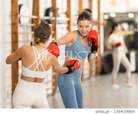 Women fight with hands, using all strength, courage during boxing lesson Women fight with hands, using all strength, courage during boxing lesson 136410008