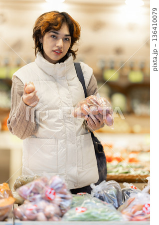 Young woman choosing onions in grocery store Young woman choosing onions in grocery store 136410079