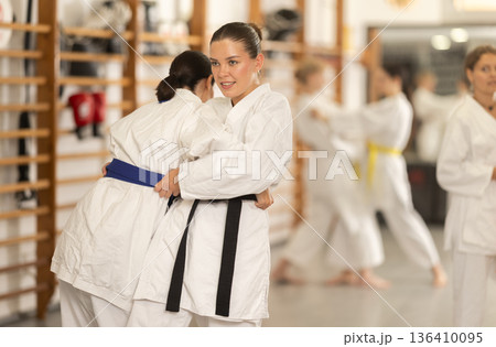 Positive young girl applying throwing technique during judo classes 136410095
