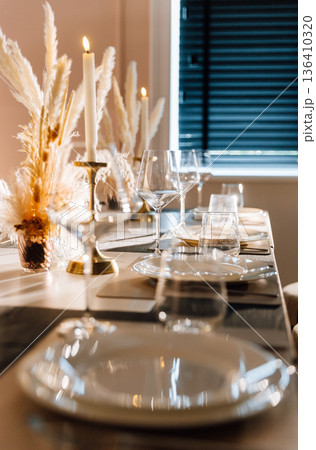 Candlelit restaurant table setting with pampas centerpiece and warm evening ambiance Candlelit restaurant table setting with pampas centerpiece and warm evening ambiance 136410320