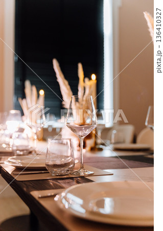 Elegant table setting with lit candle and pampas centerpiece Elegant table setting with lit candle and pampas centerpiece 136410327