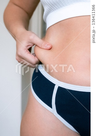 Woman weight check. Female examining torso fat indoors. Self car 136411366