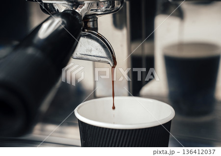 Fresh Espresso Flowing from Portafilter into Takeaway Paper Cup. High quality photo Fresh Espresso Flowing from Portafilter into Takeaway Paper Cup. High quality photo 136412037