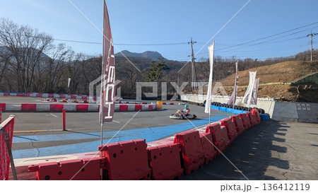 サーキットを疾走するゴーカートとドライバー 136412119