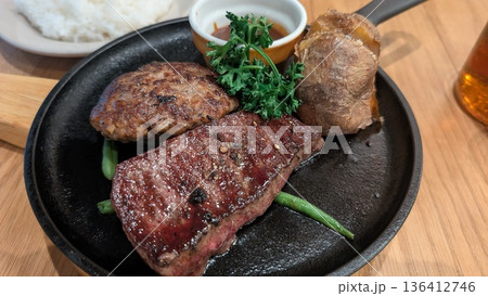 鉄板で提供されるステーキとハンバーグ 定食の盛り合わせ 136412746