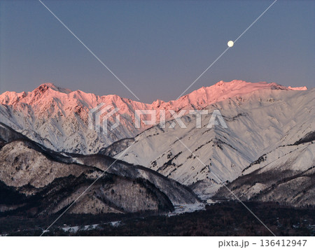 美しい唐松岳・五竜岳のモルゲンロートと沈みゆく十六夜の月　長野県白馬村（ドローンによる空撮） 136412947