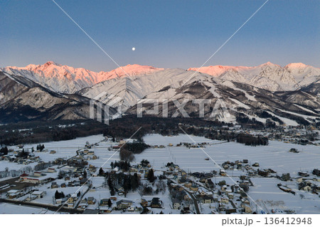 美しい白馬連峰のモルゲンロートと沈みゆく十六夜の月　長野県白馬村（ドローンによる空撮） 136412948