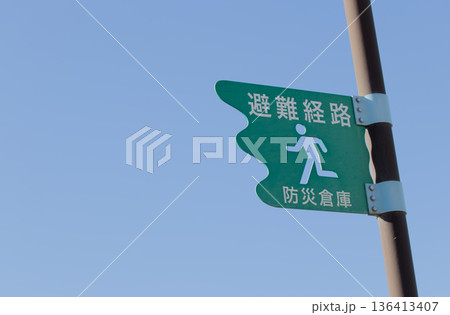 青空を背景にした避難経路・防災倉庫の案内標識　コピースペース 136413407