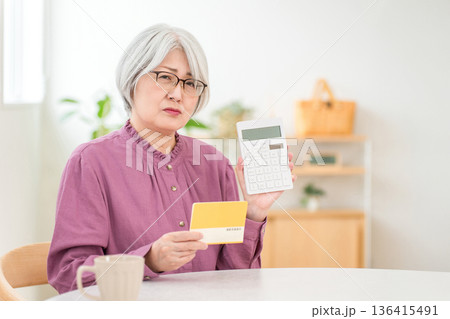 貯金通帳を見ながら電卓を使い計算するシニア女性(老後資金,生活費,年金) 貯金通帳を見ながら電卓を使い計算するシニア女性(老後資金,生活費,年金) 136415491