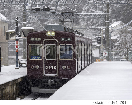雪が積もる駅に入る能勢電鉄の電車 136417013