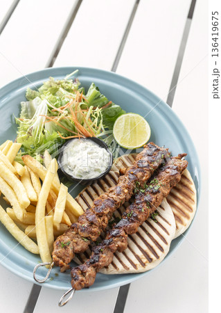 BBQ chicken skewer gyros plate on white table in mykonos restaurant greece BBQ chicken skewer gyros plate on white table in mykonos restaurant greece 136419675