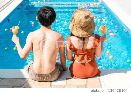 旅行先のリゾートホテルのプールサイドで遊ぶ水着姿のカップル,夫婦の後ろ姿 136420104
